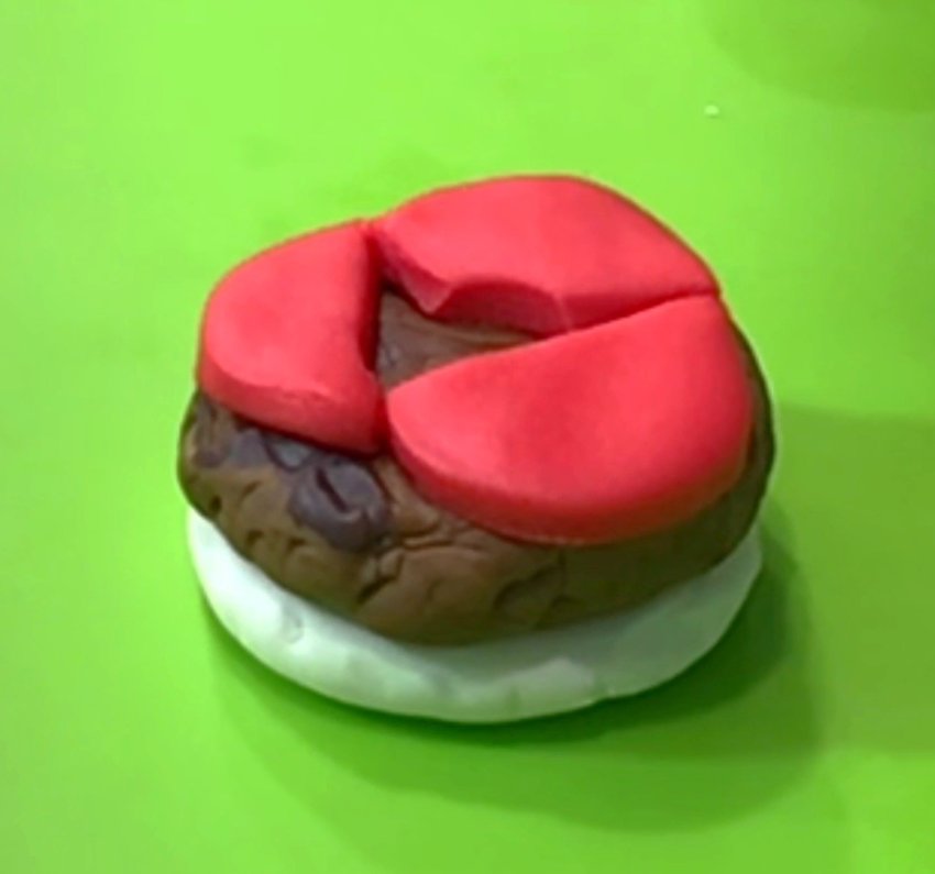 Mix fondant colors to make your choice of color for the hamburger patty. Mold to create the shape, and texture with a clay tool. Stack patty on bottom bun. Roll out red fondant. Cut to look like tomato slices. Place on top of patty.